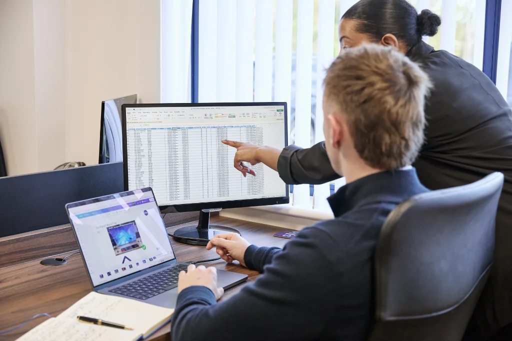 Two colleagues analysing data on computer screen in office workspace