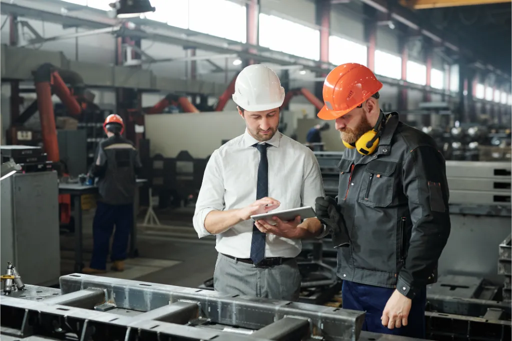 Two engineers wearing hard hats reviewing plans