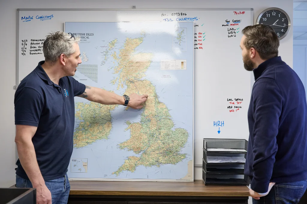 Colleagues reviewing UK map and planning logistics on whiteboard