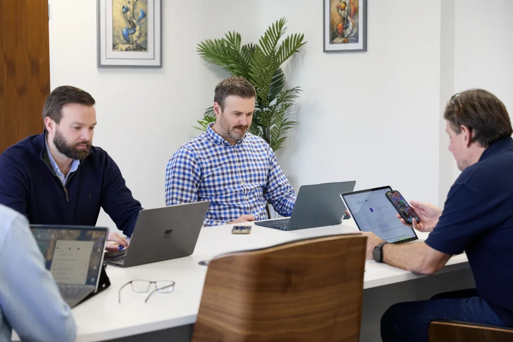 SJH colleagues working on laptops together in office meeting room