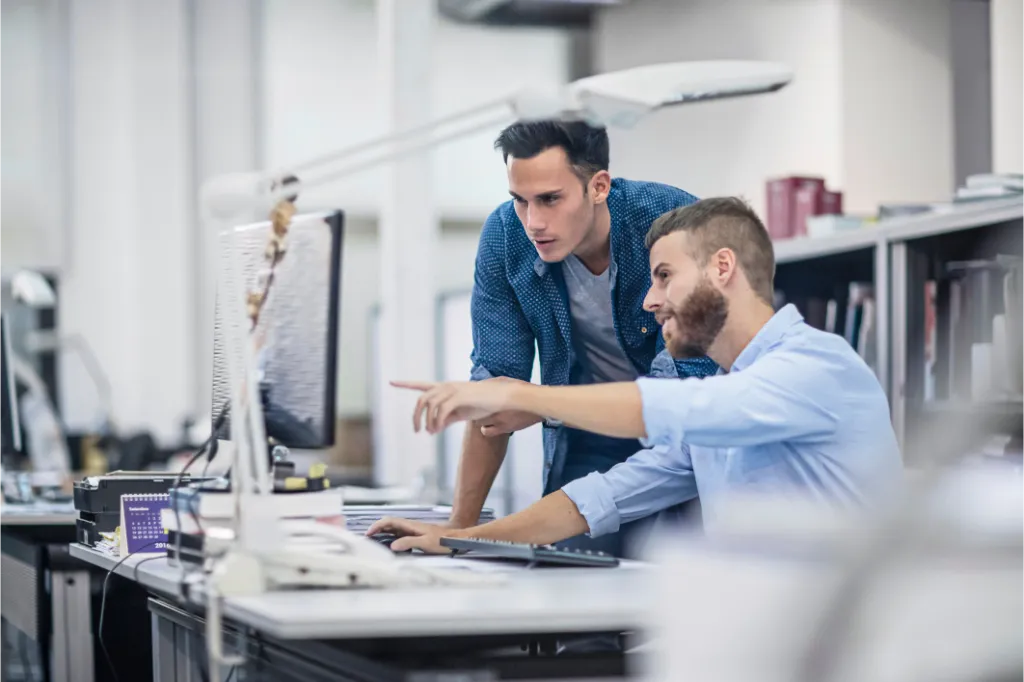 Two colleagues reviewing plans together at a desk in the office
