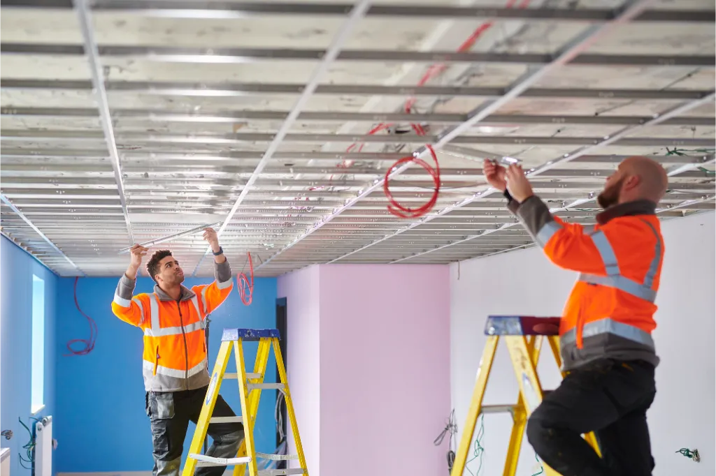 Technicians installing ceiling framework and cabling in a retail fit out