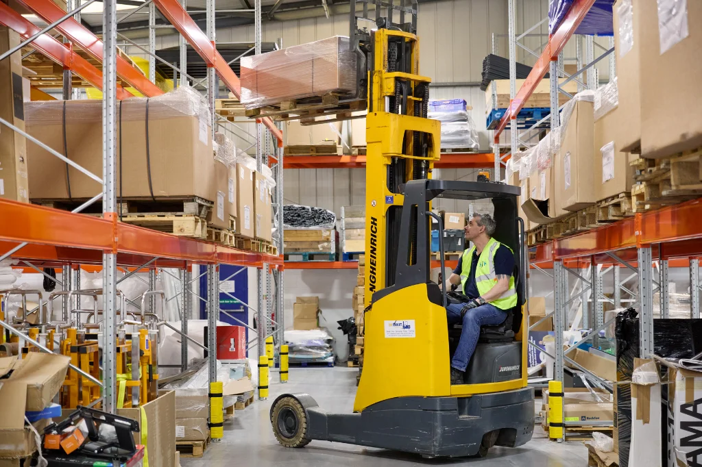 Forklift operator lifting pallet in warehouse