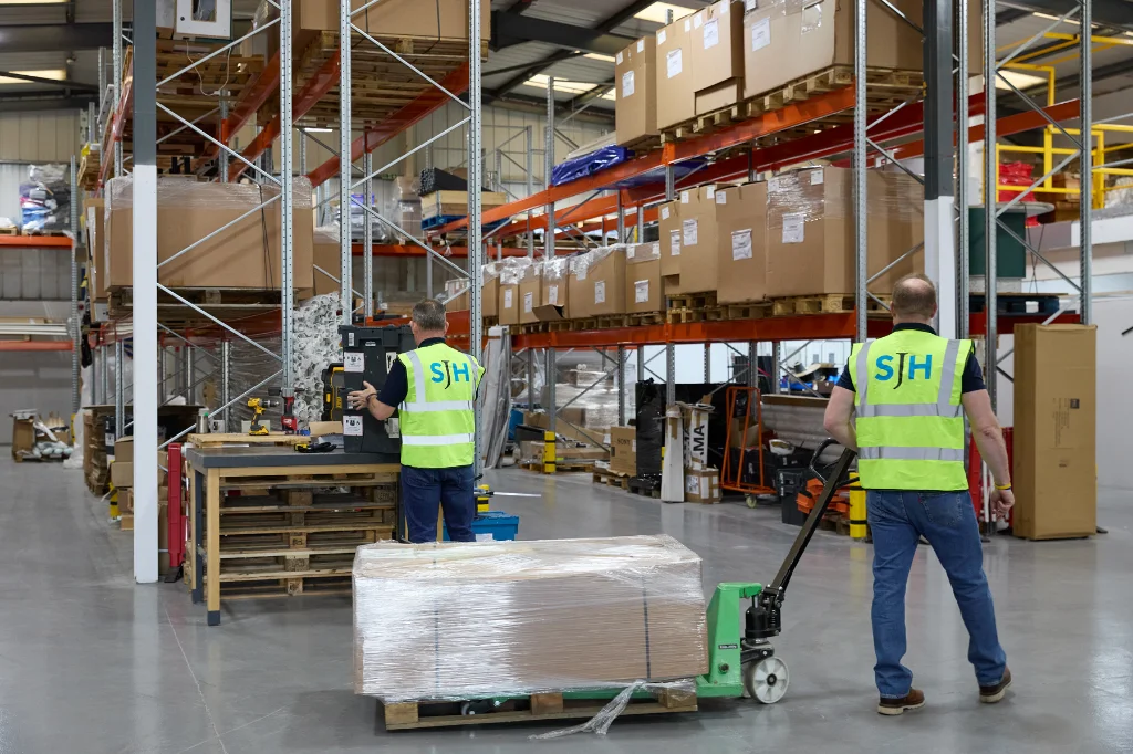SJH Warehouse staff in hi-vis vests moving pallet with manual pallet truck