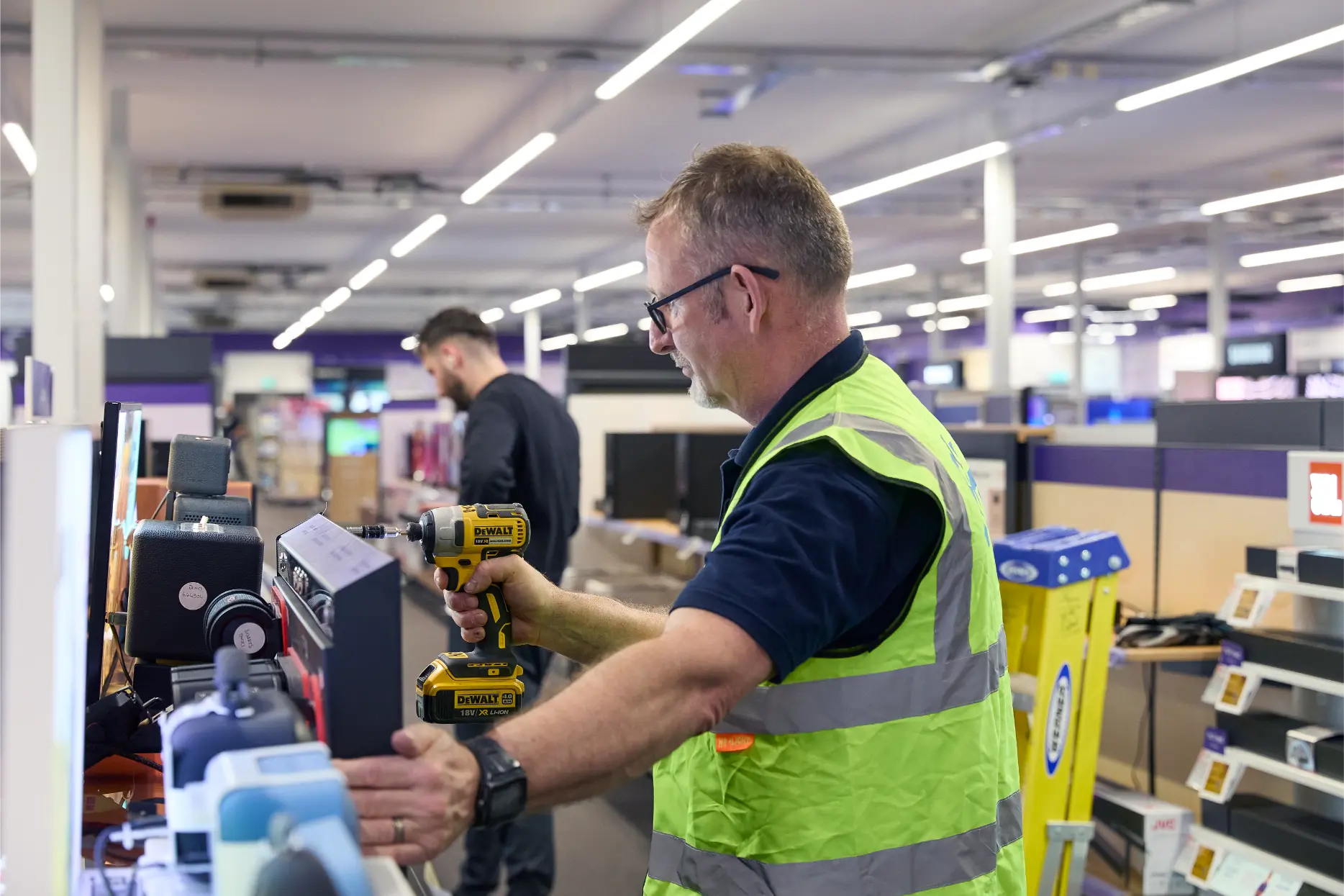 SJH Engineer installing using a power drill to install a retail display inside Currys store