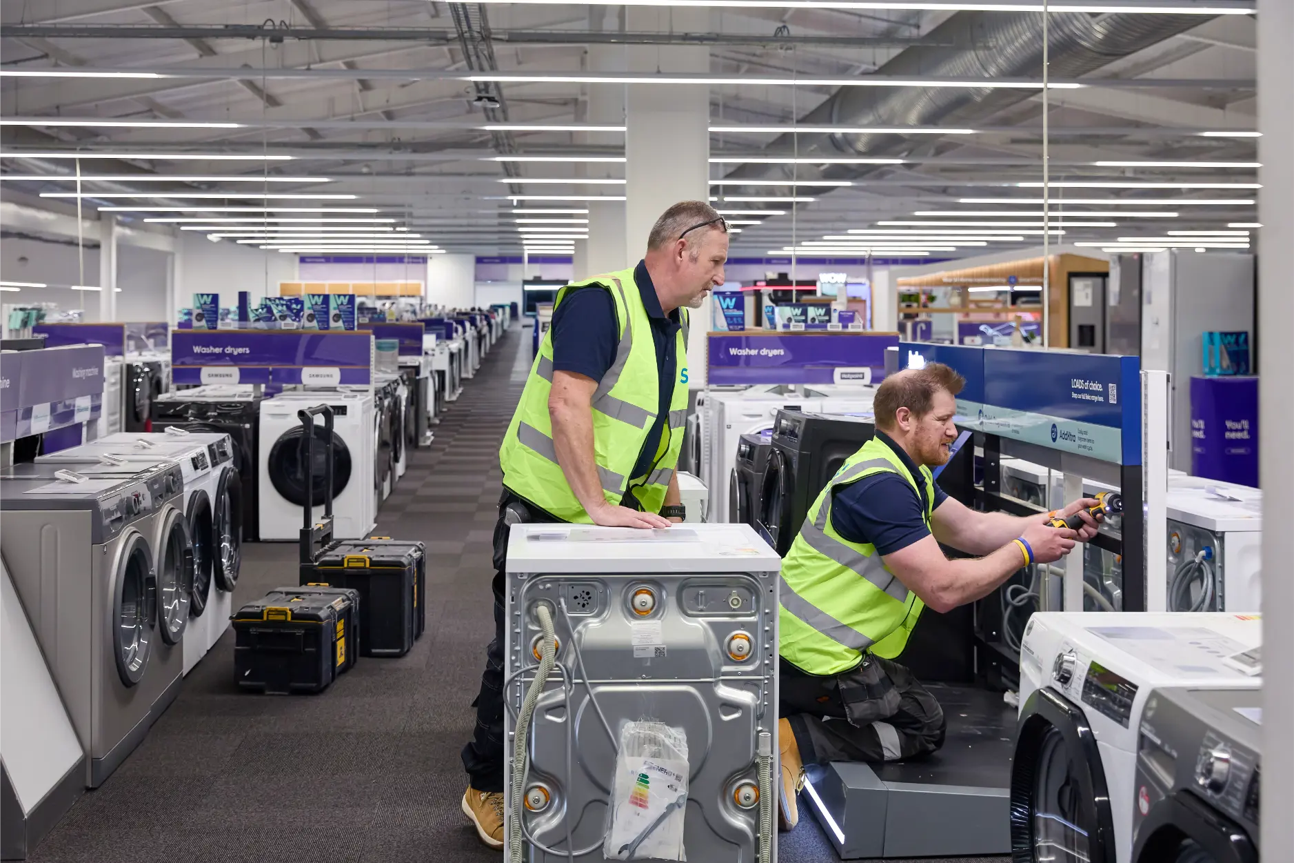 SJH installation team fitting washing machines within Currys store during retail rollout